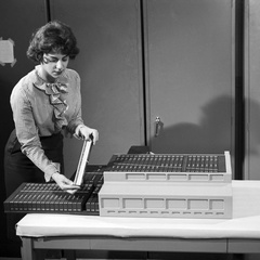A technician assembling the micrologic and core memory panels that make up the Apollo Guidance Computer into their housing